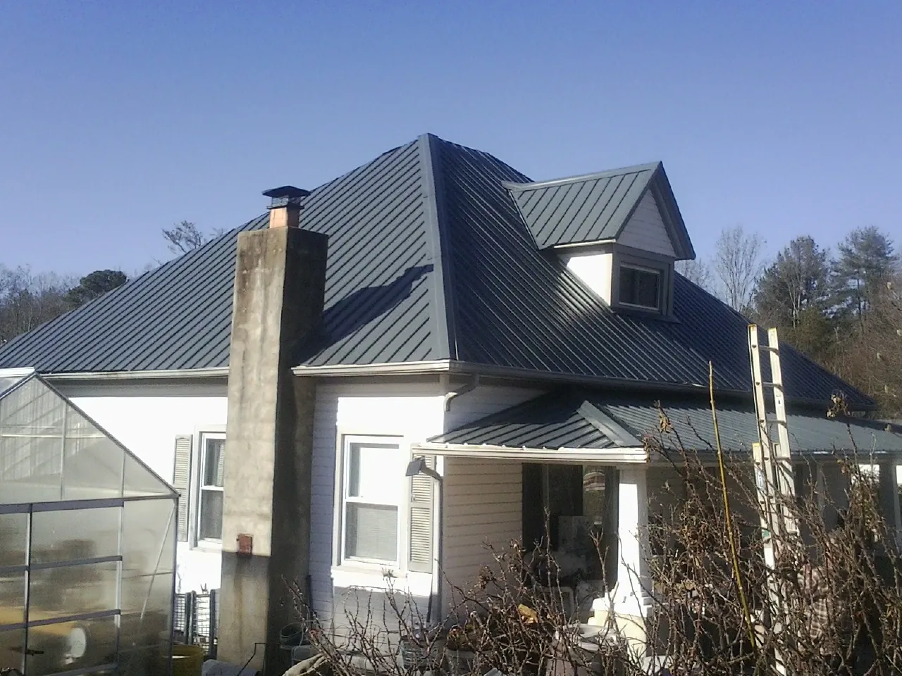 Dark blue standing seam metal roof on a white farmhouse with dormer — Slate & Tile Roof Repair by Roofing Brothers in Cocolalla