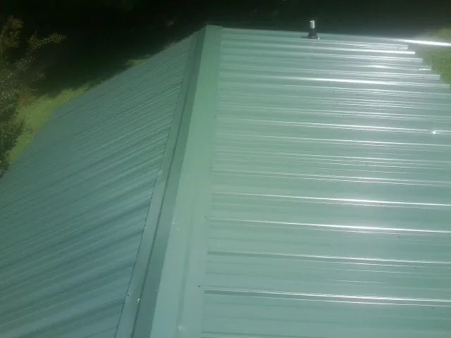 New green metal panels meeting at the ridge of a roof — Flat Roof Repair work by our crew in Cocolalla