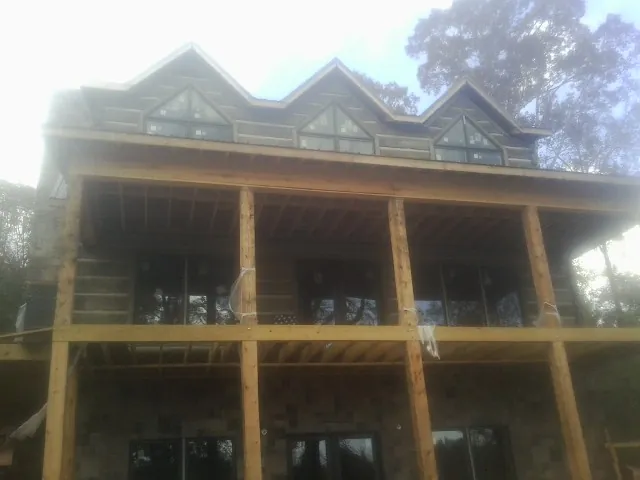 Dormers and porch framing on a large log home under construction — Roof Coating work by our crew in Cocolalla