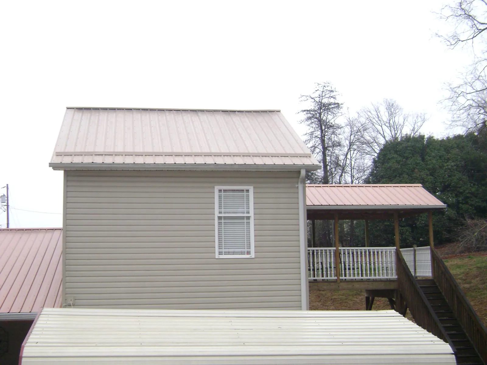 Tan metal roofs on a two story addition and attached porch, from a Roof Replacement job in Cocolalla