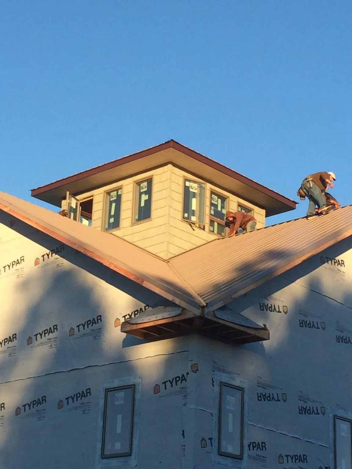 Roofers working around a rooftop cupola on a new metal roof at sunset — Roof Waterproofing in Cocolalla by Roofing Brothers